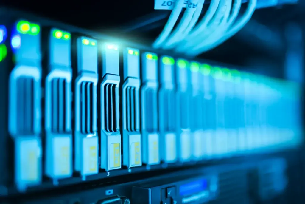 Faille Windows exploitée et fin de Windows Server 2012 : ce que le Patch Tuesday d'octobre change pour vos clients Baie de serveurs aux disques éclairés en bleu dans une salle informatique. Ces serveurs sont ceux qu'il faut corriger après le Patch Tuesday d'octobre 2026, ou migrer s'ils tournent sous Windows Server 2012.